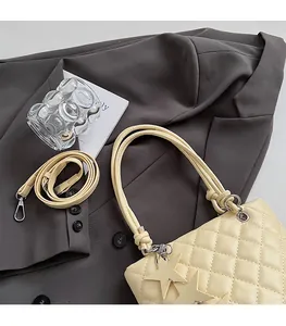 Détail du sac seau matelassé beige avec breloques étoiles et bandoulière réglable