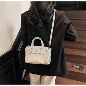 Detail of light green and beige patchwork tote bag with pebbled leather texture on model
