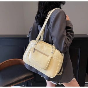 Detail of light yellow patent leather backpack with front zipper and embossed logo