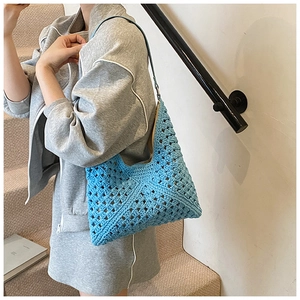 Detailed close-up of light blue crochet shoulder bag with hollow knit patterns