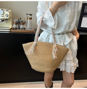 Borsa tote in paglia con manici intrecciati colorati e nappe in un ambiente luminoso di caffè