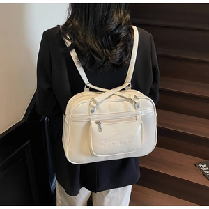 Detail of cream white leather backpack showing front zipper pocket and embossed logo