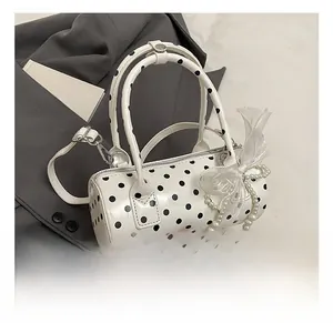 Polka dot cylindrical handbag featuring a white mesh bow and pearl charm accents