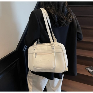 Detail of a creamy white leather backpack with front zipper pocket and silver hardware