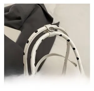 Detailed macro view of polka dot handbag handle with silver metal rivets and stitching