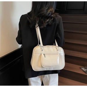 Detailed view of cream leather tote bag with embossed Noronoro logo on wooden stairs