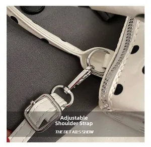 Close-up of adjustable shoulder strap with silver hardware on white polka dot bag