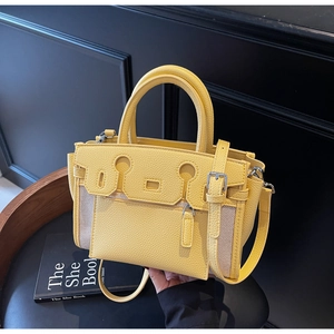 Detail of yellow lychee leather and beige canvas Kelly bag on a black chair