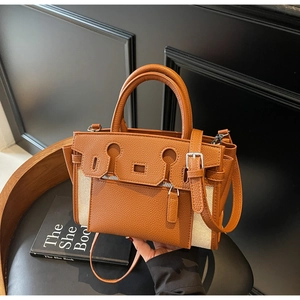 Detail of canvas and brown lychee leather handbag featuring front zipper and silver hardware