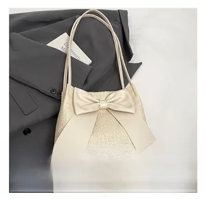 Détail montrant la texture tissée et le grand nœud crème sur le sac fourre-tout chic