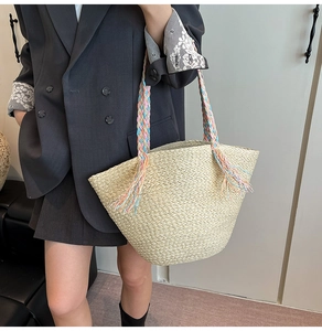 Dettaglio della borsa in paglia intrecciata a mano con manici arcobaleno e nappe colorate