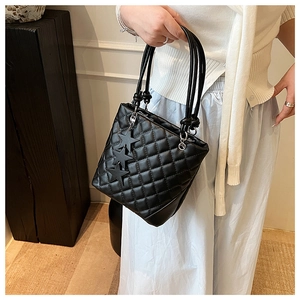 Détail d'un sac seau noir matelassé avec breloques étoiles et doubles poignées