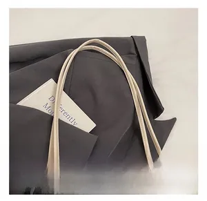 Détail des poignées en cuir crème et de la texture tressée de ce sac seau d'été