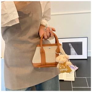 Detail of canvas tote bag with brown leather trim and cute teddy bear pendant charm