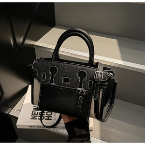 Detail of a designer two-tone leather and canvas handbag with unique zipper flap and strap