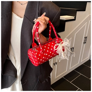 Close-up of red polka dot cylinder handbag with lace bow and pearl charm pendant