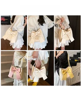 Détail d'un sac cabas en paille tressée avec un grand nœud décoratif et une bandoulière