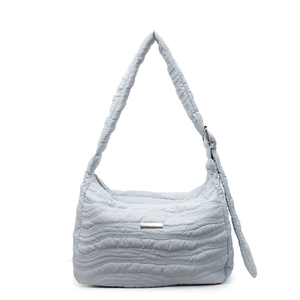 Light blue quilted shoulder bag with minimalist texture and wide strap on white background