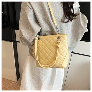 Détail d'un cabas matelassé jaune avec breloque étoile et bandoulière amovible