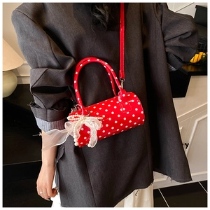 Close-up of red polka dot cylinder bag featuring white lace bow and pearl charm detail