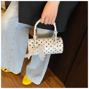 Close-up of white polka dot boston bag with pearl charm and organza bow detail