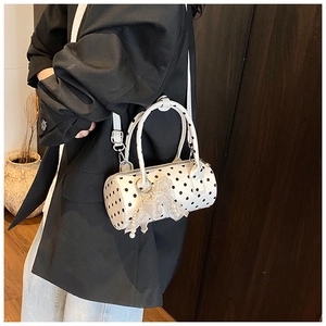Detail of white polka dot barrel bag with elegant pearl lace bow pendant and shoulder strap