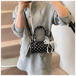 Close-up of cylinder polka dot handbag with white mesh bow and pearl bead detail