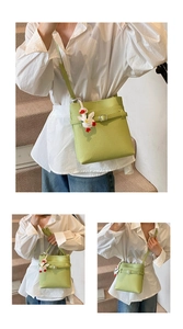Dettaglio della borsa a secchiello verde avocado con texture litchi e ciondolo papera