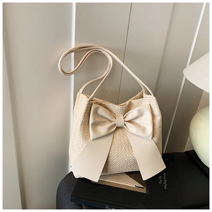 Détail d'un sac cabas tissé crème avec un grand nœud décoratif et une finition texturée