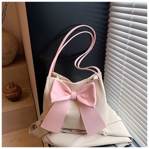 Détail du sac seau en paille tissée avec un grand nœud rose et de fines bretelles roses
