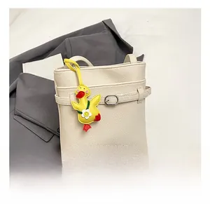 Dettaglio della borsa a secchiello in pelle litchi bianco crema con ciondolo a forma di papera