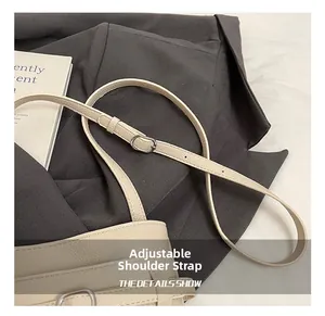 Dettaglio borsa a secchiello in pelle beige con fibbia regolabile argento su un blazer