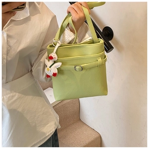 Détail du sac seau vert clair à texture litchi avec ceinture décorative et canard