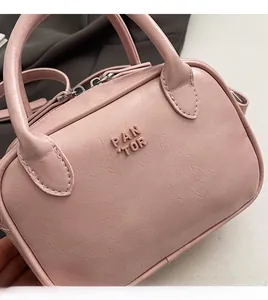 Gros plan d'un sac Boston rose montrant le cuir grainé et le logo embossé PAN TOR