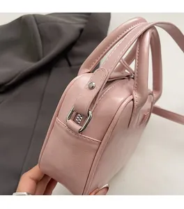 Détail d'un sac à main en cuir rose clair avec fermetures éclair et doubles anses
