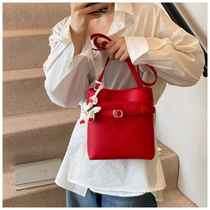 Détail du sac seau rouge à motif litchi avec une breloque peluche canard blanc mignon