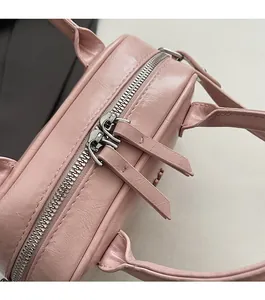 Détail du sac à main en similicuir rose avec double fermeture éclair et texture grainée