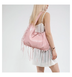Détail du sac hobo en cuir verni rose avec pompons à franges et large bandoulière