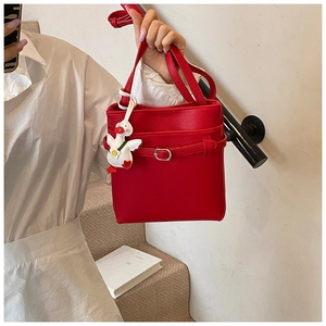 Détail du sac seau en cuir grainé rouge avec boucle argentée et breloque canard