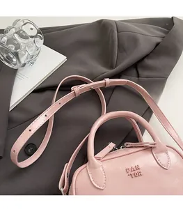 Gros plan du sac à main rose en cuir PU avec logo PAN TOR embossé sur un blazer gris