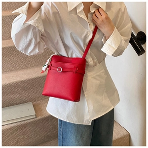 Détail du sac seau rouge à texture lychee avec un petit pendentif fraise mignon