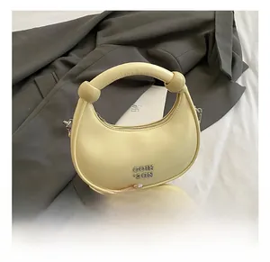 Detailed view of the yellow crescent bag featuring a knotted handle and silver metal logo