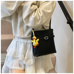 Détail du sac seau noir en cuir grainé avec un charmant canard en peluche jaune