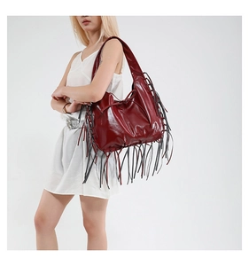 Detail view of burgundy leather tote bag featuring long black tassels and a chic bow knot