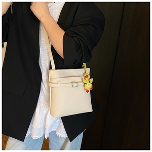 Détail du sac bandoulière blanc cassé avec texture litchi et pendentif canard jaune
