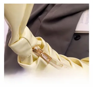 Detail of premium gold-tone zipper and unique knot strap design on yellow soft leather bag