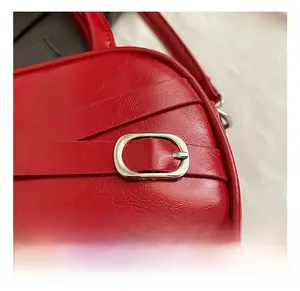 Macro detail of red leather handbag showing silver oval metal buckle and fine texture