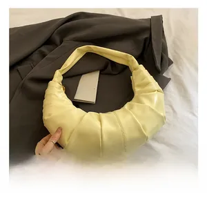 Close-up of soft pleated crescent bag in pale yellow faux leather texture