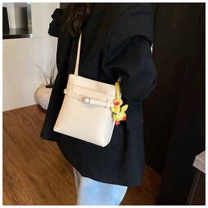 Gros plan du sac seau blanc cassé avec motif litchi et un pendentif canard jaune