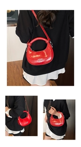 Macro shot of red crescent bag showing round handle, silver lettering and zipper detail